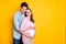 Photo of young couple closed eyes stand hug pregnant woman wear casual outfits isolated on yellow color background