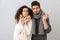 Photo of young couple man and woman wearing scarfs holding lemons and ginger, isolated over gray background