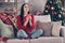 Photo of young cute lady sit couch hold cup eyes closed sniff smell wear red sweater jeans socks in decorated living
