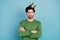 Photo of young egoistic selfish smiling guy in crown folded arms wear green jumper isolated on blue color background