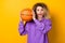 Photo of young excited girl have fun sporty play basketball workout isolated over yellow color background