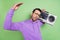 Photo of young excited man hold retro boombox music disco dance isolated over green color background