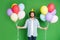 Photo of young funny man hold many balloons blow whistle wear paper cone hat denim shirt jeans isolated green color
