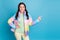 Photo of young girl look show point finger empty space choice choose promo ad wear yellow pants isolated over blue color