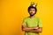 Photo of young handsome man crossed hands wear crown unhappy look empty space wear green t-shirt isolated over yellow