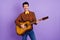 Photo of young handsome positive cheerful romantic man playing acoustic guitar on date isolated on violet color