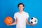 Photo of young happy positive man hold hands basketball football isolated on pastel blue color background