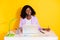 Photo of young happy positive smiling afro woman working in laptop writing in organizer isolated on yellow color