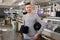 photo of a young man with black threads in cones in his hands near industrial knitting machines