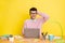 Photo of young man clueless confused no answer study online laptop isolated over yellow color background