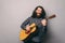 Photo of young man with long hair and beard paying at acoustic guitar