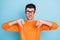 Photo of young man unhappy sad upset bite tongue teeth show thumb-down bad quality dislike ad isolated over blue color