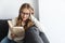 Photo of young pleased woman reading book while sitting on couch