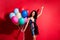 Photo of young pretty girl hold many balloons raise up hand wear glossy short dress isolated vibrant red color