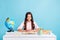 Photo of young pretty smiling focused calm peaceful girl sitting desk reading doing homework isolated on blue color