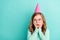 Photo of young school girl amazed shocked hands touch cheeks wear birthday cap look empty space isolated over teal color