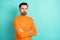Photo of young serious handsome man confident crossed hands wear orange sweater isolated over turquoise color background