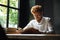 Photo of young smiling readhead bearded man in white shirt reading book