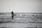 Photo of young surfer with surf board. Man standing in the sea and looking waves. Ready for surfing. Horizontal