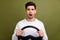 Photo of young surprised man holding steering wheel crazy riding automobile with manual gearbox isolated on khaki color