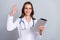 Photo of young woman cardiologist use modern device show fingers okey symbol recommend isolated over grey color