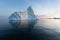 Photogenic and intricate iceberg under an interesting and blue sky during sunset. Effect of global warming in nature.