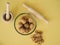 Photograph from above of a still life mounted on a yellow background and composed of a kneader, a glass bowl and some nuts