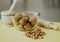 Photograph from above of a still life mounted on a yellow background and composed of a kneader, a glass bowl and some nuts