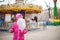 A photograph of a child`s rest on nature in the spring. A child girl in a bright pink jacket is eating sweet cotton wool against t