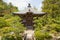 Photograph of the front of a Japanese wooden temple surrounded by plants