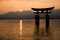 Photograph of the great torii of Miyajima surrounded by water at sunset