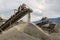 A photograph of the heavy machinery at the quarry, rocks and sand conveyor belt.