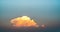 A photograph of a large golden-yellow cloud in the twilight colored sky in the evening.