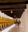 A photograph of row of statues of Buddha with lady walking down the corridor