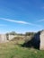 Photograph of ruins amidst a green landscape against a slightly cloudy blue sky