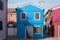 Photograph taken on a sunny day of blue house in square of brightly coloured houses on the island of Burano, Venice.