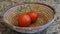 A photograph of a two ripe tomatoes in a basket