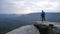 Photographer in blue jacket stand on rocky view point and taking photos of misty morning landscape. Hike in rocks.