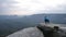 Photographer in blue jacket stand on rocky view point and taking photos of misty morning landscape. Hike in rocks.