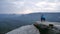 Photographer in blue jacket warm clothes stand on rocky view point and taking photos of misty morning landscape. Hike in rocks.