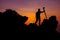 Photographer climbing on the top of the mountain to take a picture at sunset