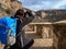 Photographer crouching in the middle of a sandy path taking a picture in the middle of the mountain