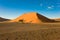 Photographer in front of huge orange dune in Namibia. Dune in Namib Desert, Namibia
