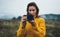 Photographer girl hold in hands video camera take photo on background autumn froggy mountain, tourist shooting nature mist