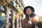 Photographer in glasses with retro photo camera. Tourist portrait. Smile girl in hat travels in Barcelona holiday. Sunlight flare