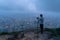 A photographer hiking and looking at city on rock, mountain hill in Hong Kong downtown in adventure concept during travel trip,