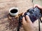 The photographer is intending to use digital camera take pictures a cup of blak coffee and coffee beans