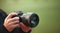 Photographer men shooting images. Man hands holding camera taking photos. Vivid blur green background