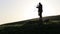 Photographer opens tripod mechanism and sets up camera at top of the green hill.