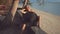 Photographer positions model on beach wearing black sunhat